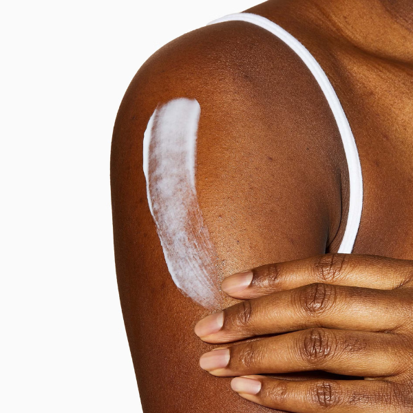 Vrouw brengt CeraVe Hydraterende Crème 454g aan op de schouder voor intensieve verzorging van droge huid.