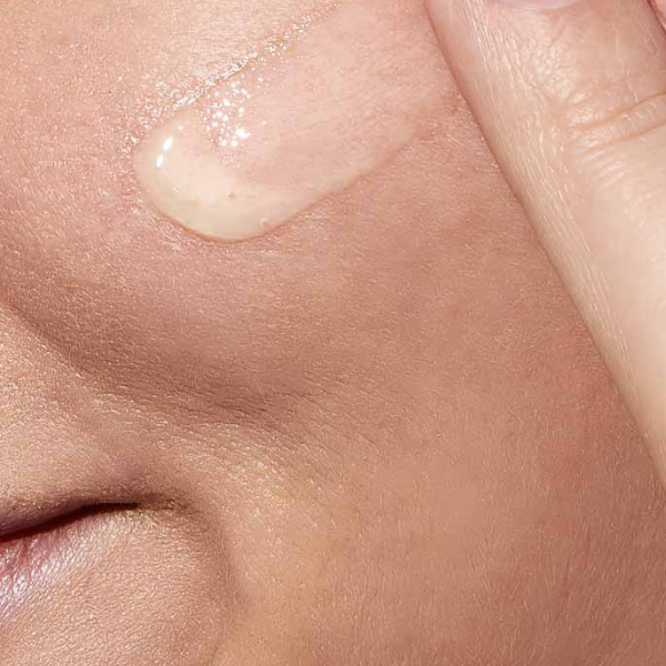 Close-up van gezicht waarop CeraVe Resurfacing Retinol Serum wordt aangebracht met vingertoppen, laat lichte geltextuur zien.
