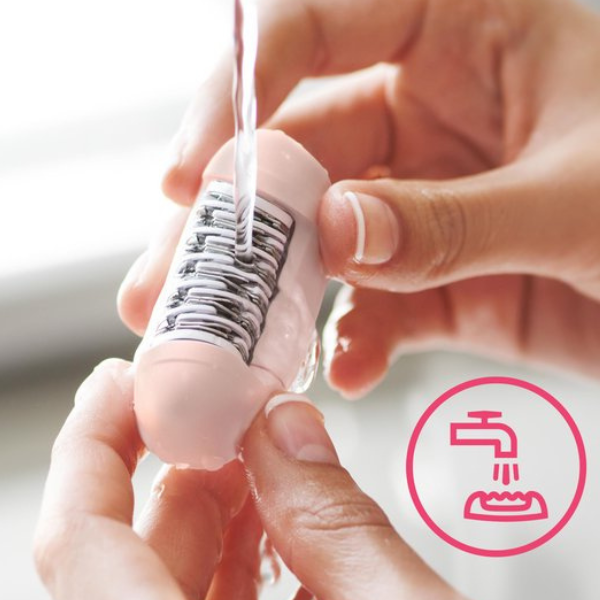 Close-up van Philips BRE235/00 epilator die onder stromend water wordt schoongespoeld, met roze icoon dat wasbaarheid aangeeft.